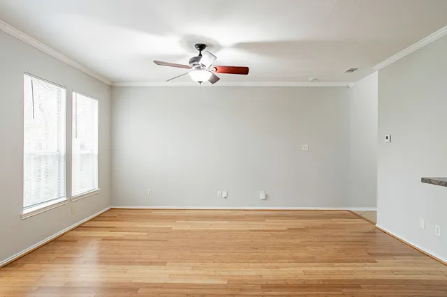 a view of an empty room with window and wooden floor