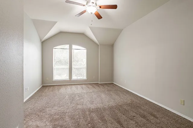 an empty room with chandelier fan and windows