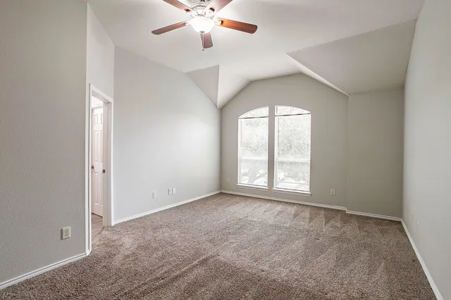 an empty room with windows and chandelier fan
