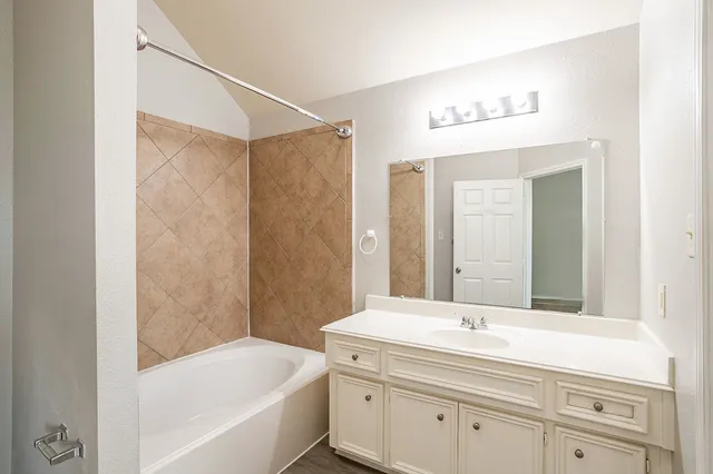 a bathroom with a tub a sink and mirror