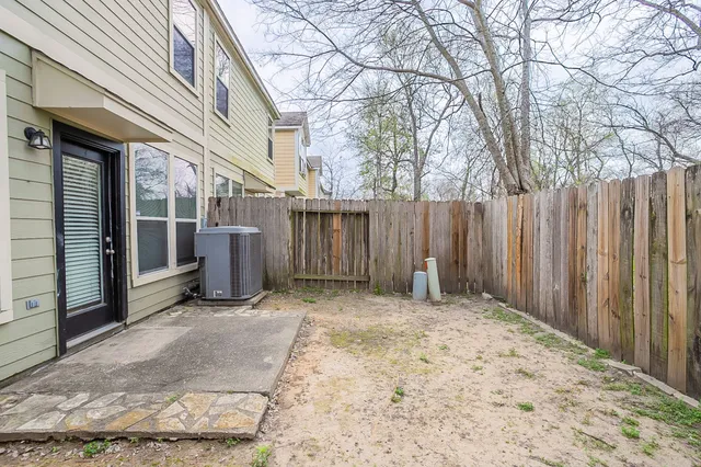 a view of backyard with large trees and wooden fence