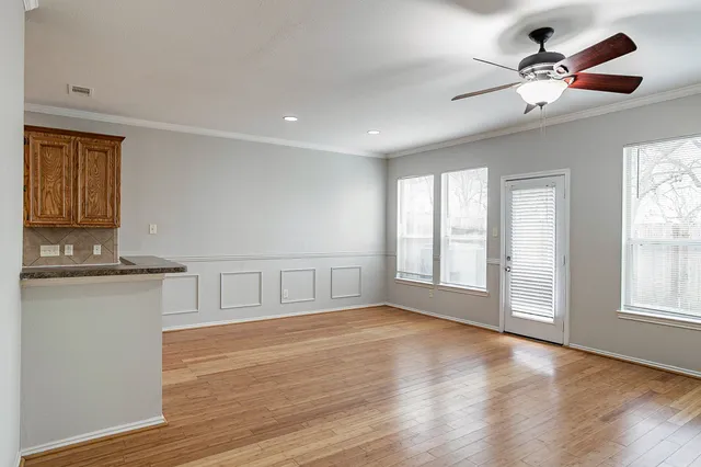 a view of an empty room with a window and wooden floor