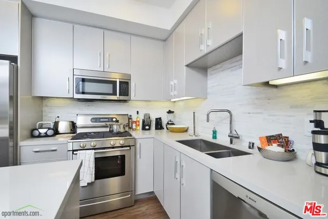 a kitchen with stainless steel appliances granite countertop a sink a stove top oven and white cabinets