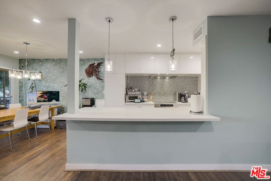 1045 North Kings Road, Unit 102 West Hollywood, CA 90069 - Photo 3 of 15 a view of a kitchen with kitchen island stainless steel appliances a sink table and chairs