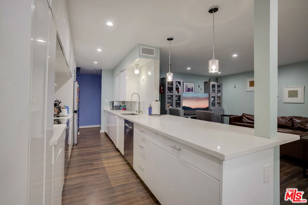 1045 North Kings Road, Unit 102 West Hollywood, CA 90069 - Photo 4 of 15 a kitchen with kitchen island a sink appliances and cabinets