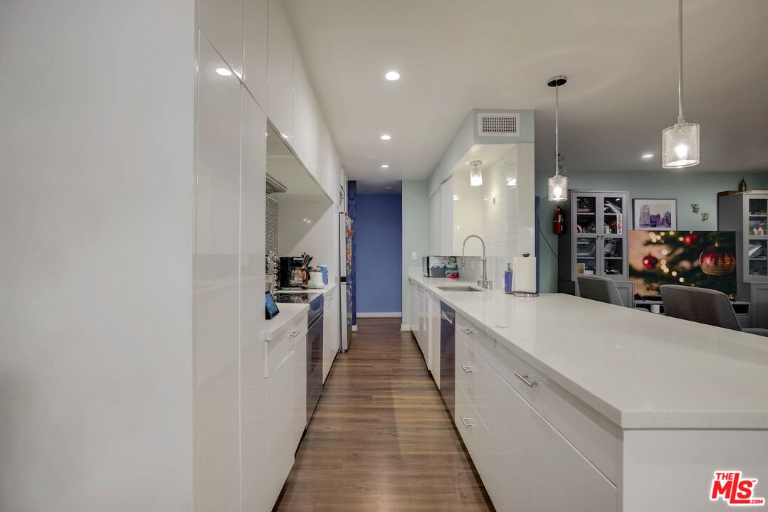 1045 North Kings Road, Unit 102 West Hollywood, CA 90069 - Photo 5 of 15 a large white kitchen with a large counter top appliances and cabinets