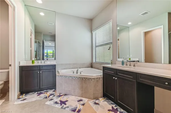 a bathroom with a sink double vanity granite tub and a mirror