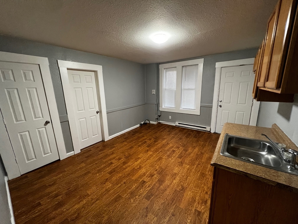691 State Street Springfield, MA 01109 - Photo 8 of 18 an empty room with wooden floor and cabinets