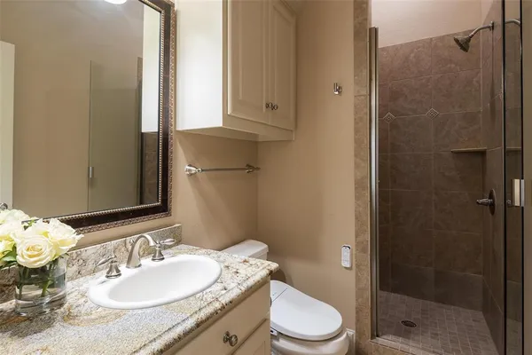 a bathroom with a granite countertop sink toilet a mirror and shower
