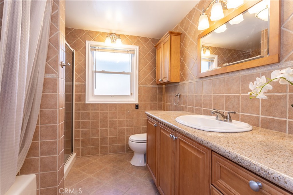 18308 Lahey Street Porter Ranch, CA 91326 - Photo 25 of 41 a bathroom with a granite countertop sink a toilet and a mirror