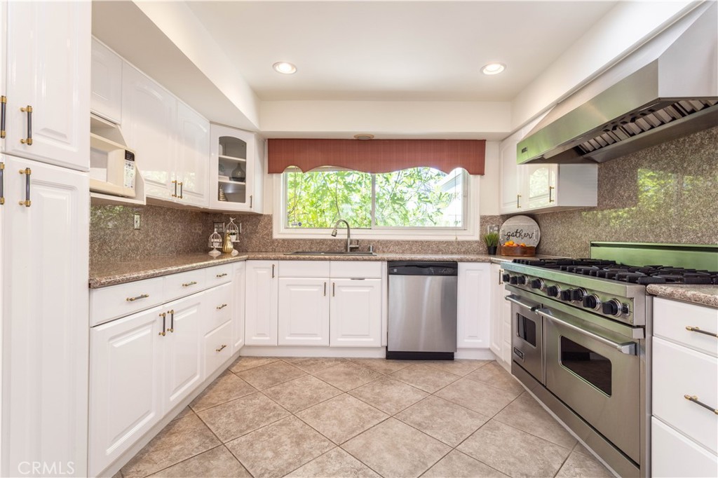 18308 Lahey Street Porter Ranch, CA 91326 - Photo 9 of 41 a kitchen with granite countertop white cabinets and appliances