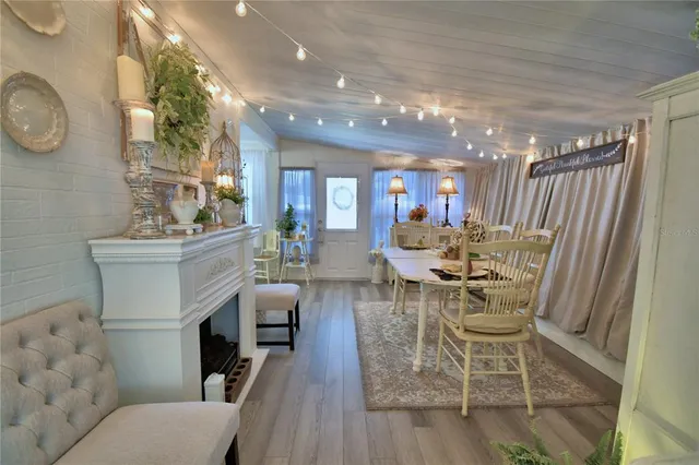 a view of a dining room with furniture a fireplace and wooden floor