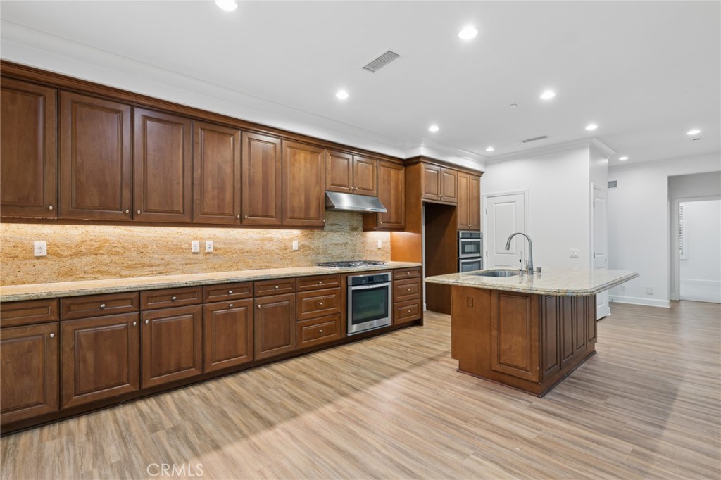 40 Lupari Irvine, CA 92618 - Photo 11 of 56 a kitchen with stainless steel appliances granite countertop a sink dishwasher stove and wooden cabinets with wooden floor