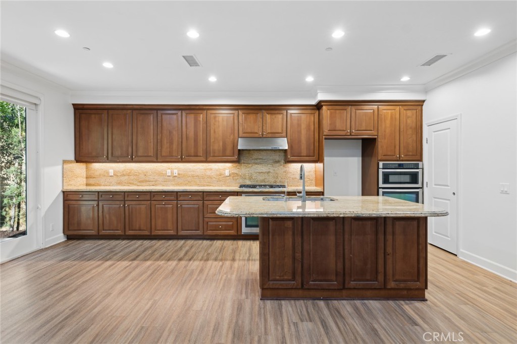 40 Lupari Irvine, CA 92618 - Photo 5 of 56 a kitchen with kitchen island a sink dishwasher a stove and a refrigerator with wooden floor