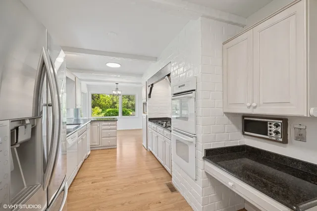 a kitchen with white cabinets and black stainless steel appliances