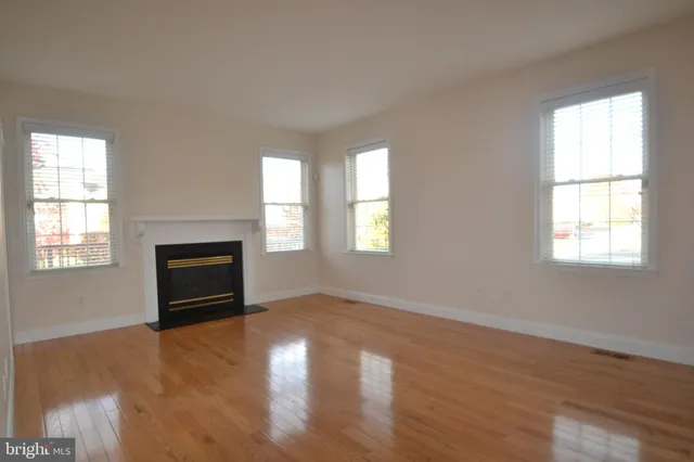 a view of empty room with a fireplace and wooden floor