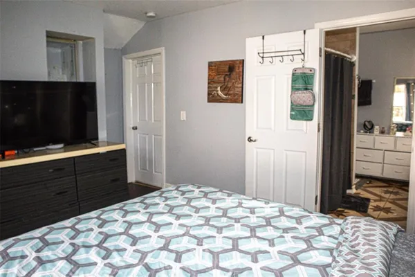 a bedroom with a bed and a flat tv screen on dresser