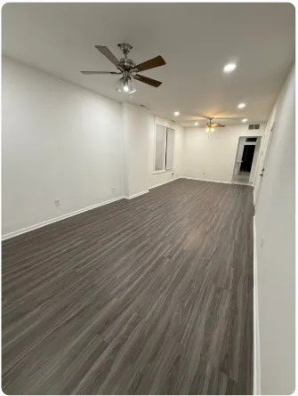 an empty room with wooden floor closet and fan