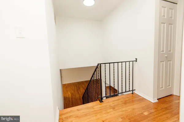 a view of an empty room with wooden floor and stairs