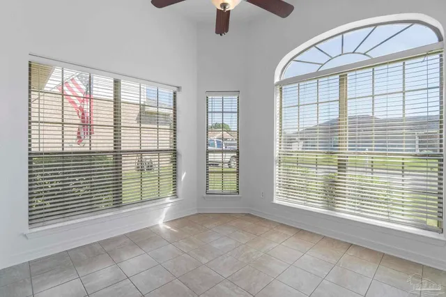 an empty room with wooden floor chandelier fan and windows