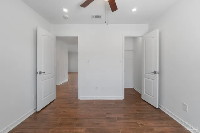 an empty room with wooden floor and a ceiling fan