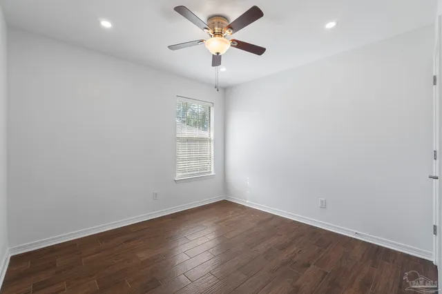 an empty room with wooden floor ceiling fan and window