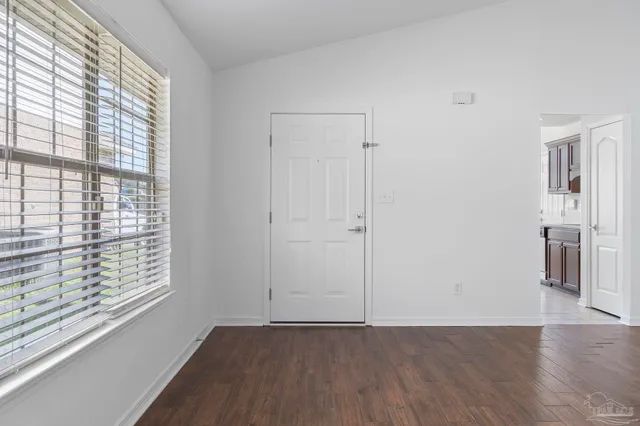 an empty room with wooden floor chandelier fan and windows