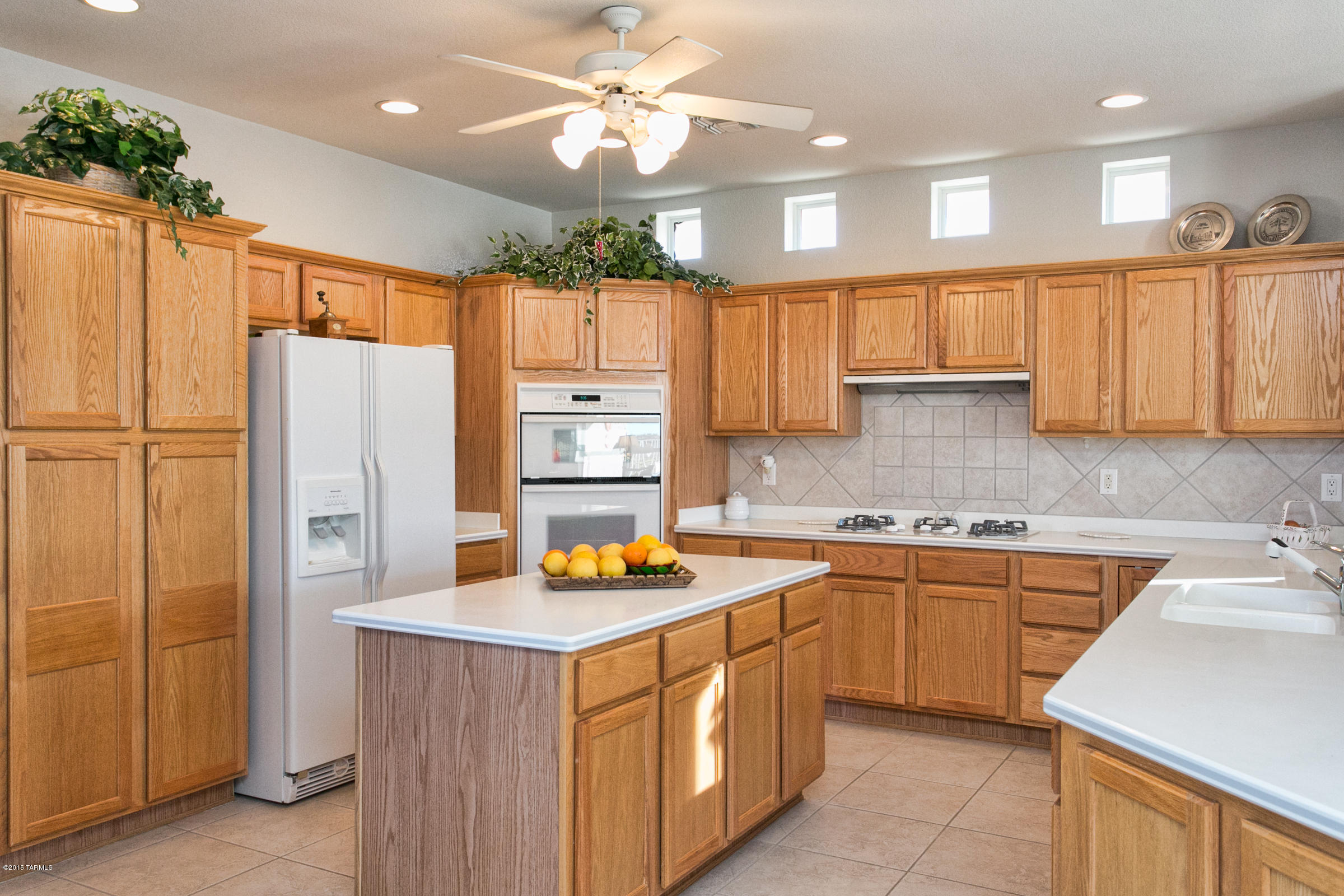 62419 East Northwood Road Tucson, AZ 85739 - Photo 2 of 30 a kitchen with stainless steel appliances granite countertop a refrigerator a sink dishwasher and white cabinets with wooden floor