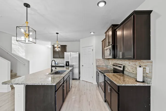 a kitchen with stainless steel appliances granite countertop a sink stove and refrigerator