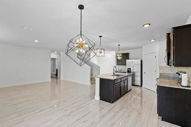 a kitchen with stainless steel appliances granite countertop a sink dishwasher a refrigerator and a wooden floor