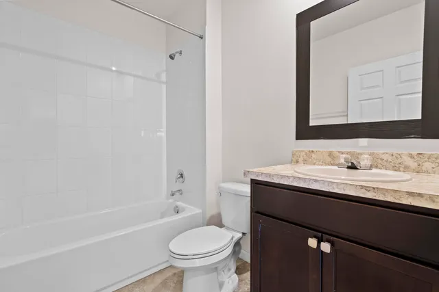a bathroom with a granite countertop sink toilet mirror and bathtub