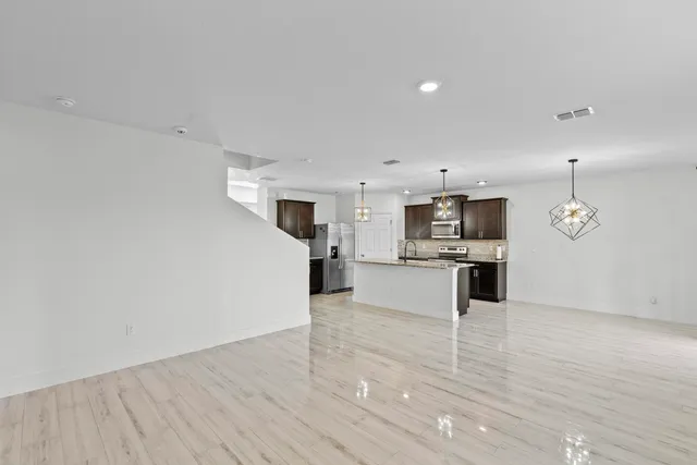 a large white kitchen with wooden floor and stainless steel appliances