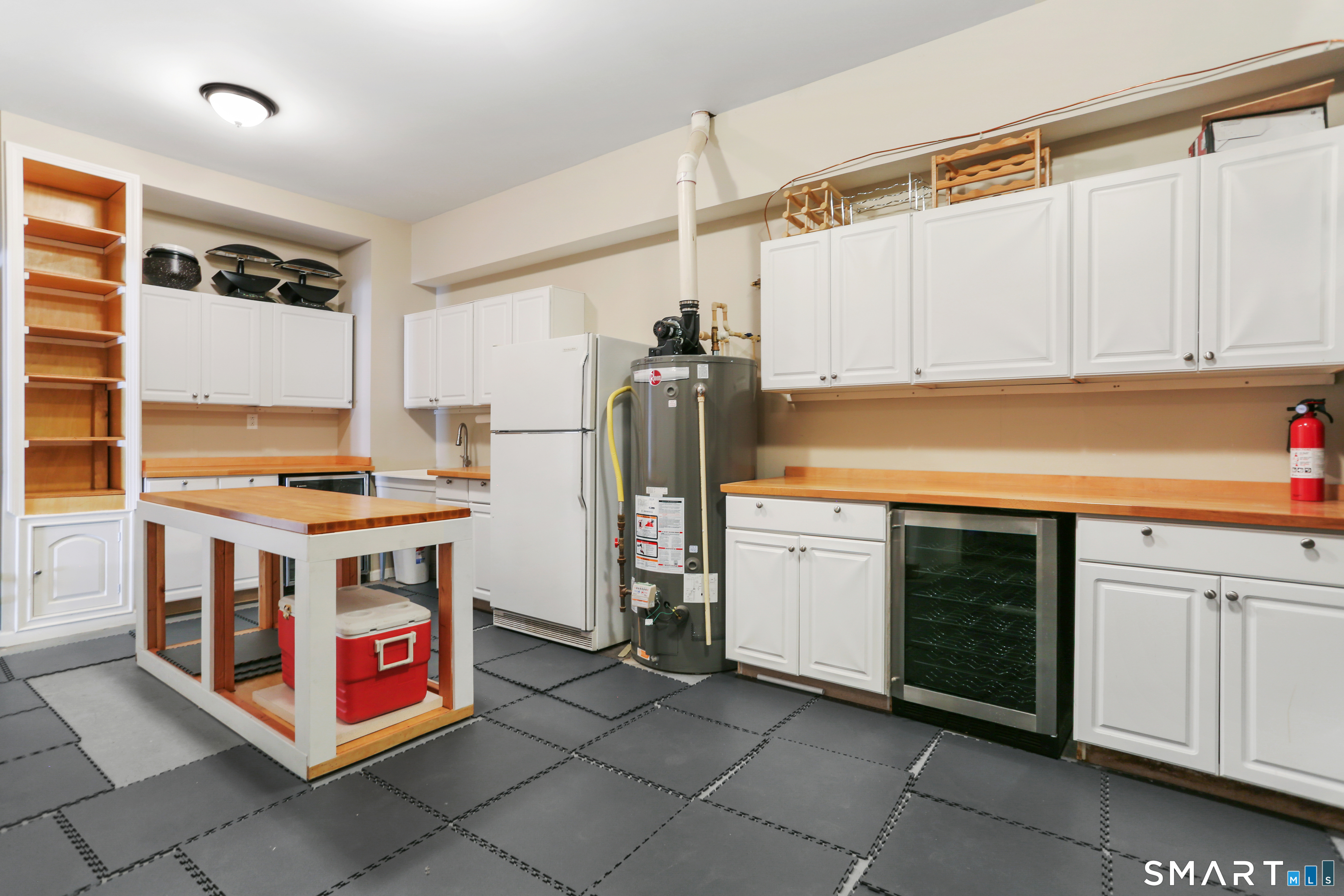 2 Trout Creek Road, Unit 2 Shelton, CT 06484 - Photo 33 of 38 Versatile lower-level workroom featuring custom cabinetry, sink, beverage refrigerator, and full-size refrigerator. Poly-coated butcher block countertops and island create excellent workspace, finished with durable Supra Tile flooring.