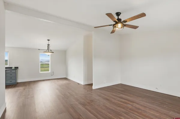 a view of empty room with wooden floor and fan