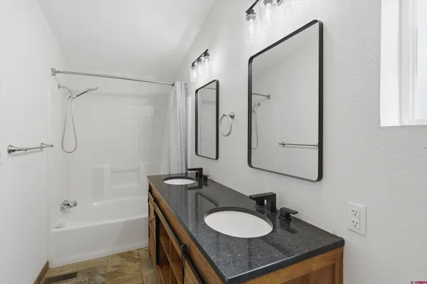 a bathroom with a granite countertop sink a mirror a vanity and bathtub