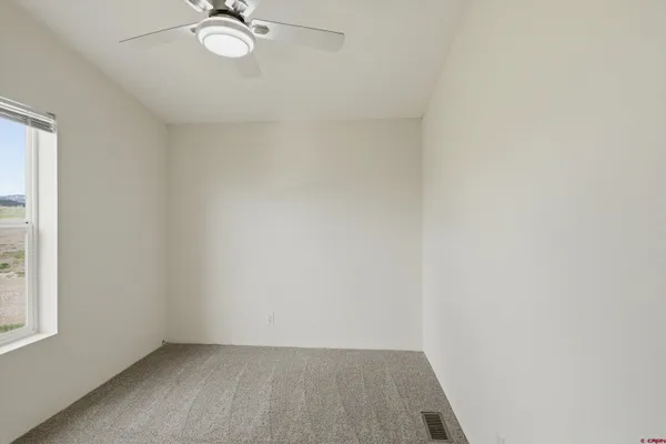 an empty room with a window and a fan
