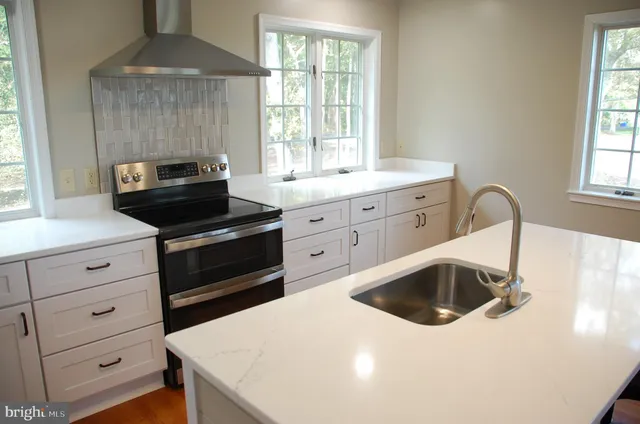 a kitchen with white cabinets a sink a stove and a window