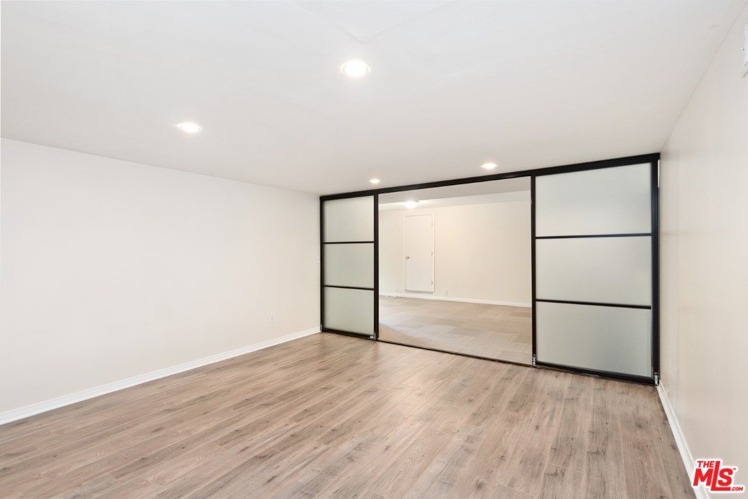 9614 Heather Road Beverly Hills, CA 90210 - Photo 19 of 25 an empty room with wooden floor and white walls