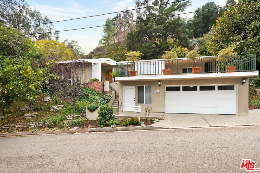 9614 Heather Road Beverly Hills, CA 90210 - Photo 22 of 25 a front view of a house with a yard and garage