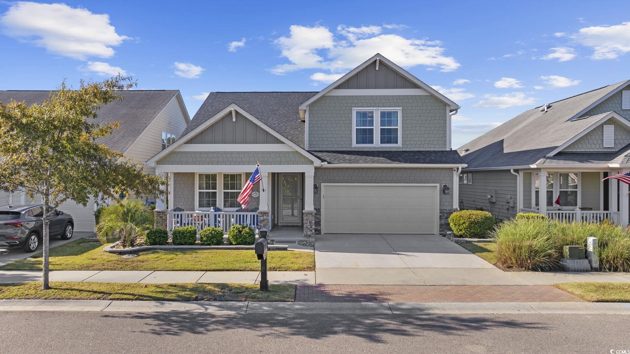 Craftsman-style home with a porch, concrete driveway, roof with shingles, a front yard, and board and batten siding