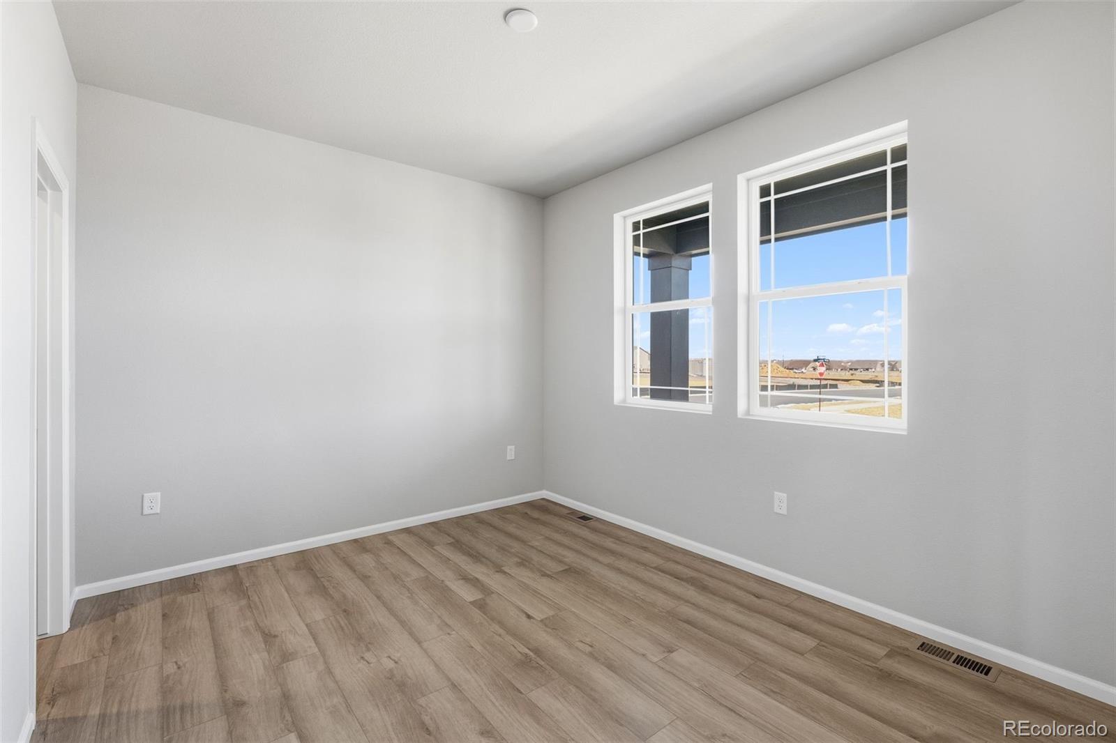 15293 Olive Way Thornton, CO 80602 - Photo 12 of 29 a view of an empty room with wooden floor and a window