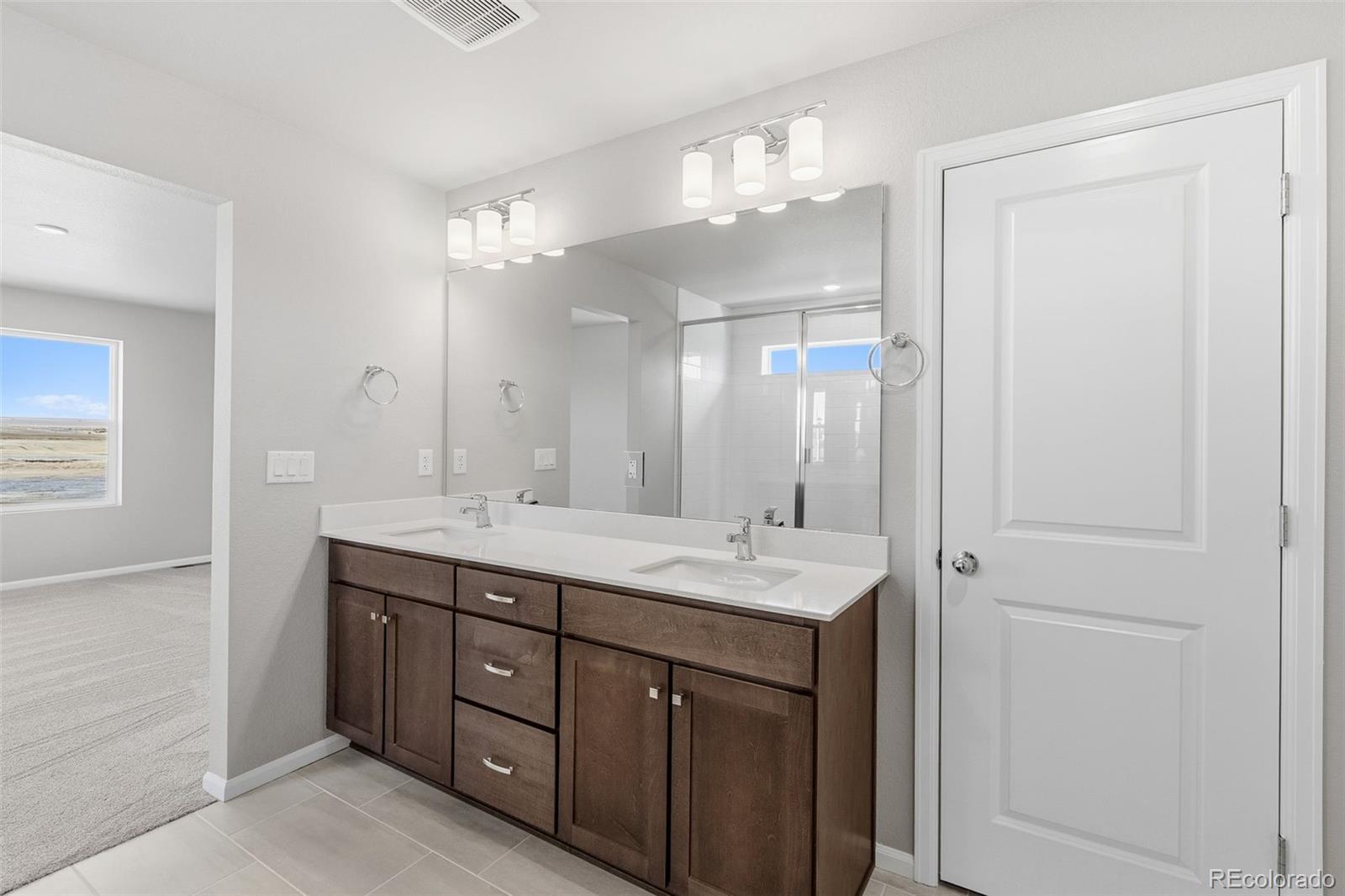 15293 Olive Way Thornton, CO 80602 - Photo 16 of 29 a bathroom with a double vanity sink and a mirror