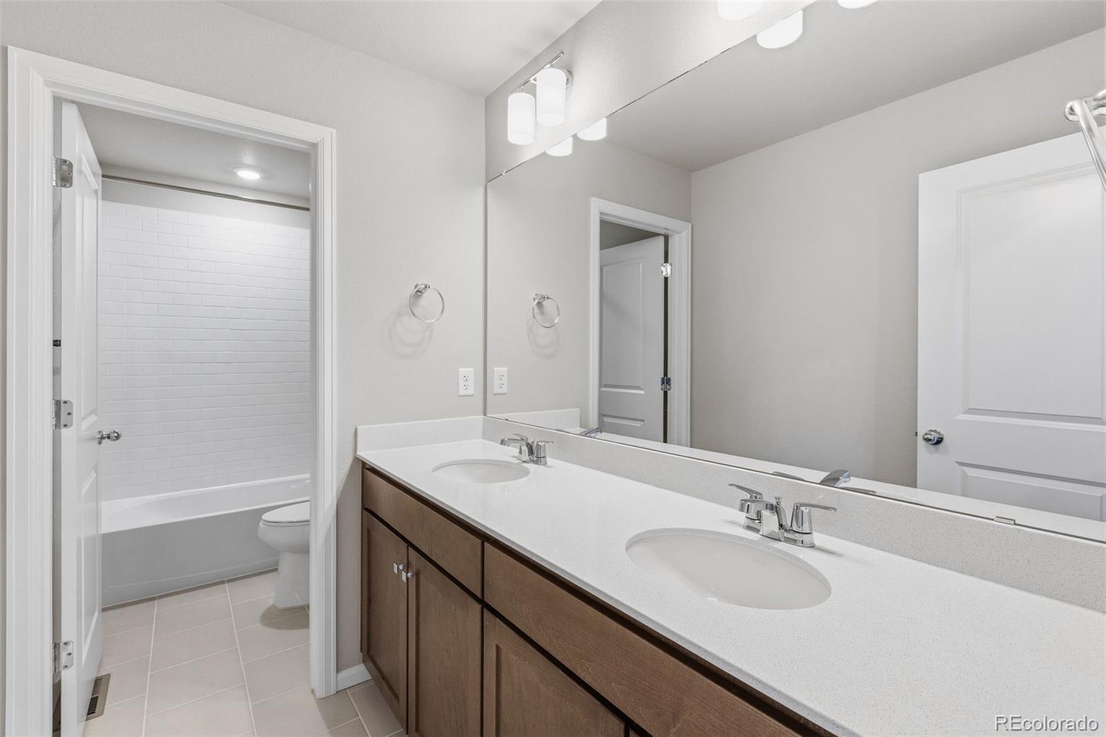 15293 Olive Way Thornton, CO 80602 - Photo 22 of 29 a bathroom with a sink double vanity granite tub shower and a mirror