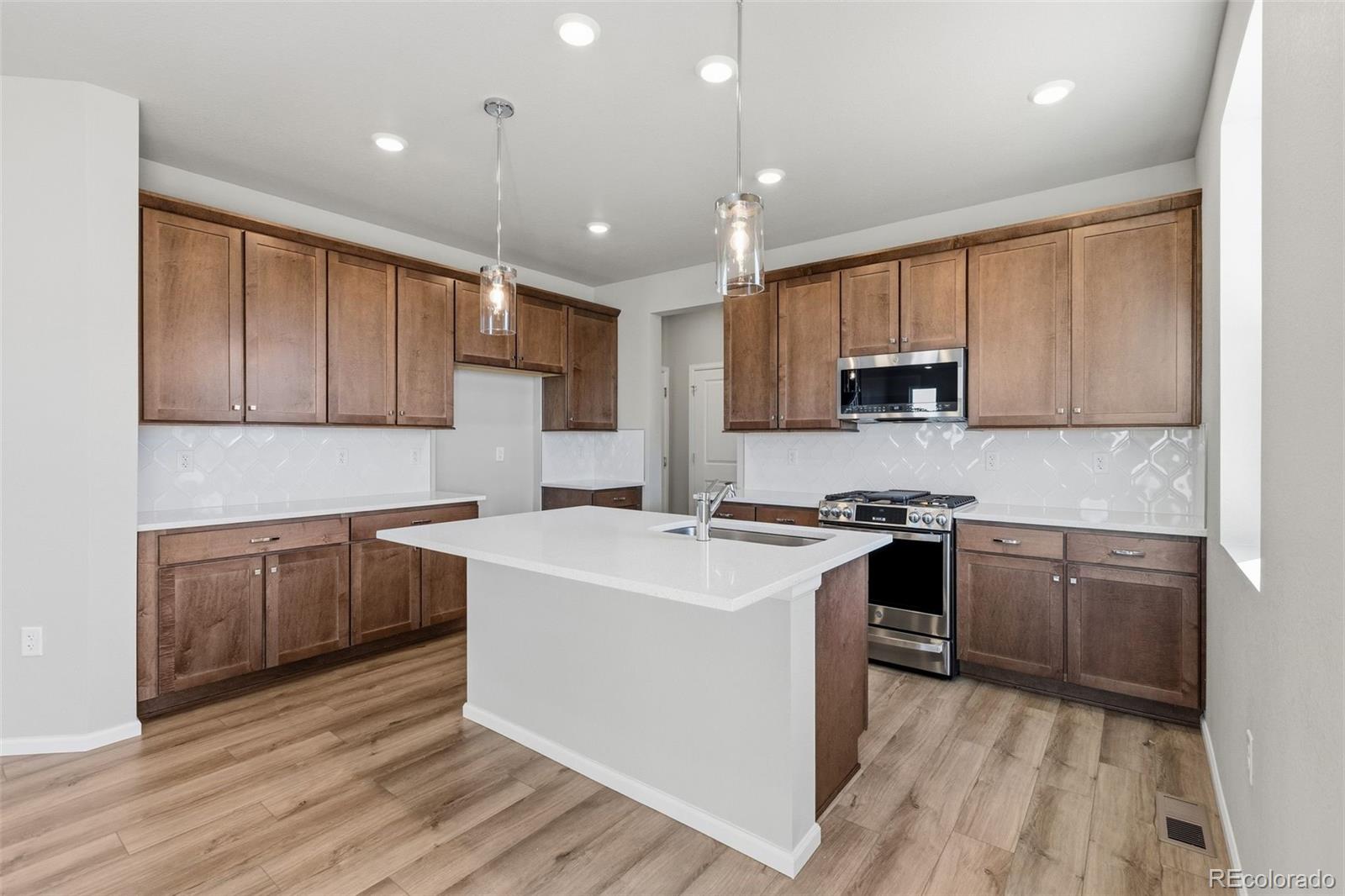 15293 Olive Way Thornton, CO 80602 - Photo 3 of 29 a kitchen with kitchen island granite countertop wooden cabinets and white appliances