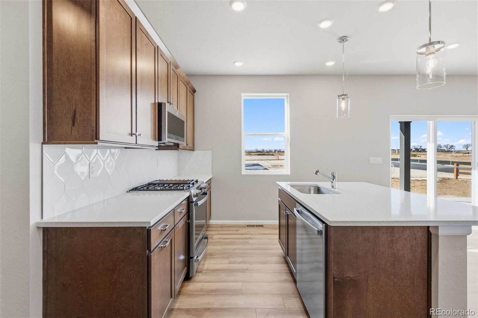 15293 Olive Way Thornton, CO 80602 - Photo 4 of 29 a kitchen with a sink stove and cabinets