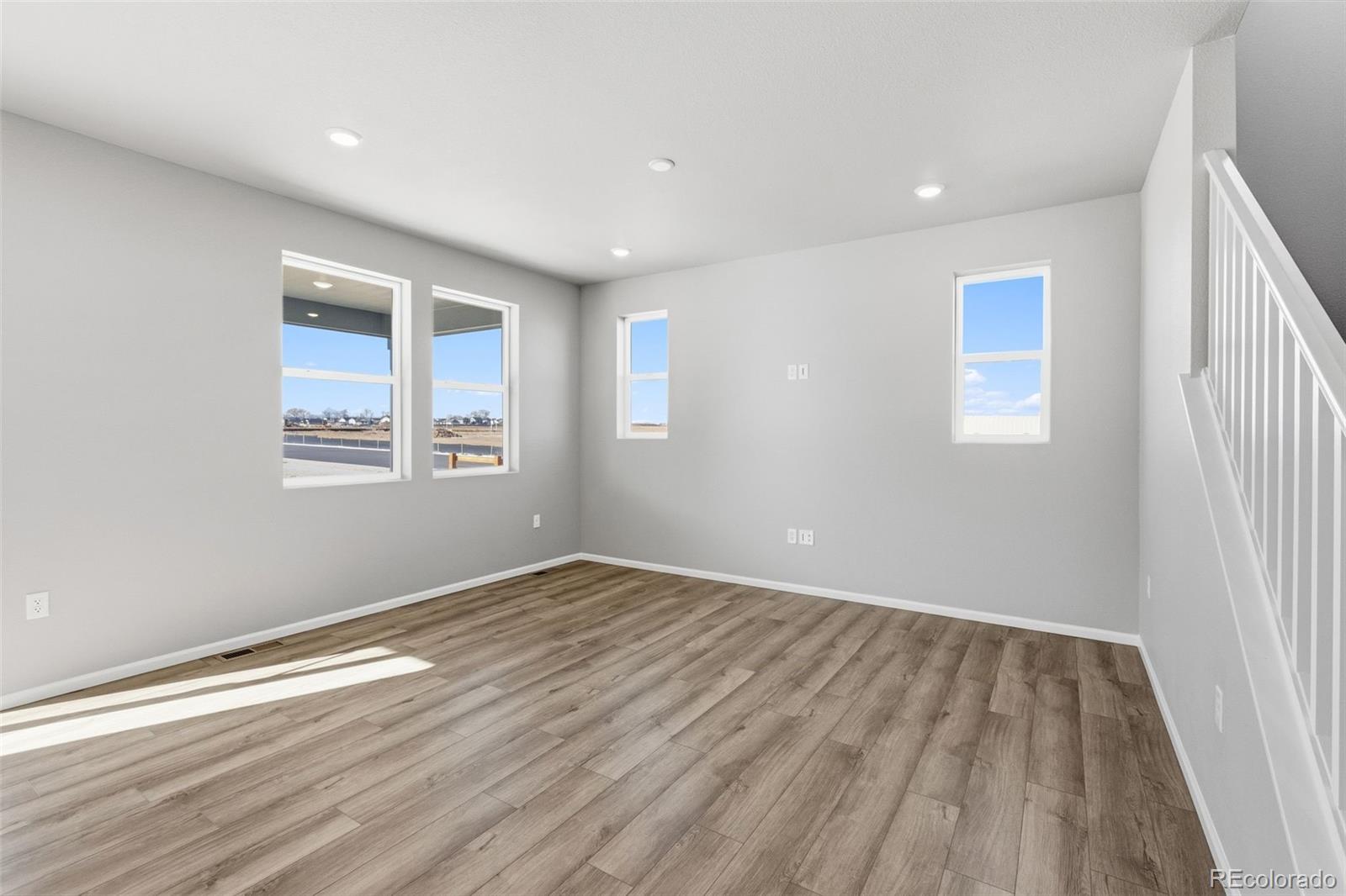 15293 Olive Way Thornton, CO 80602 - Photo 10 of 29 an empty room with wooden floor and windows