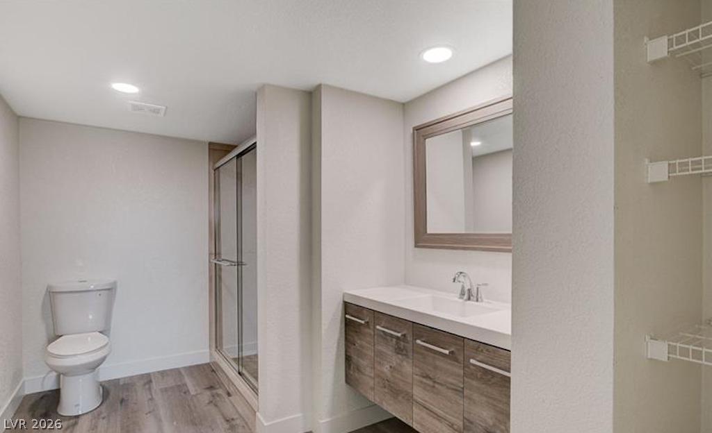 8101 West Flamingo Road, Unit 2014 Las Vegas, NV 89147 - Photo 6 of 13 Recessed lighting illuminates this modern bathroom complete with a glass-enclosed shower and wood-look flooring.