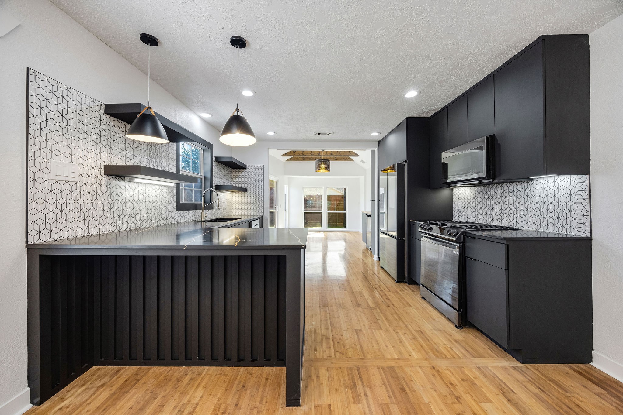 1310 Walton Street Houston, TX 77009 - Photo 5 of 19 Stylish kitchen with oversized island, modern cabinetry, designer backsplash, and pendant lighting.