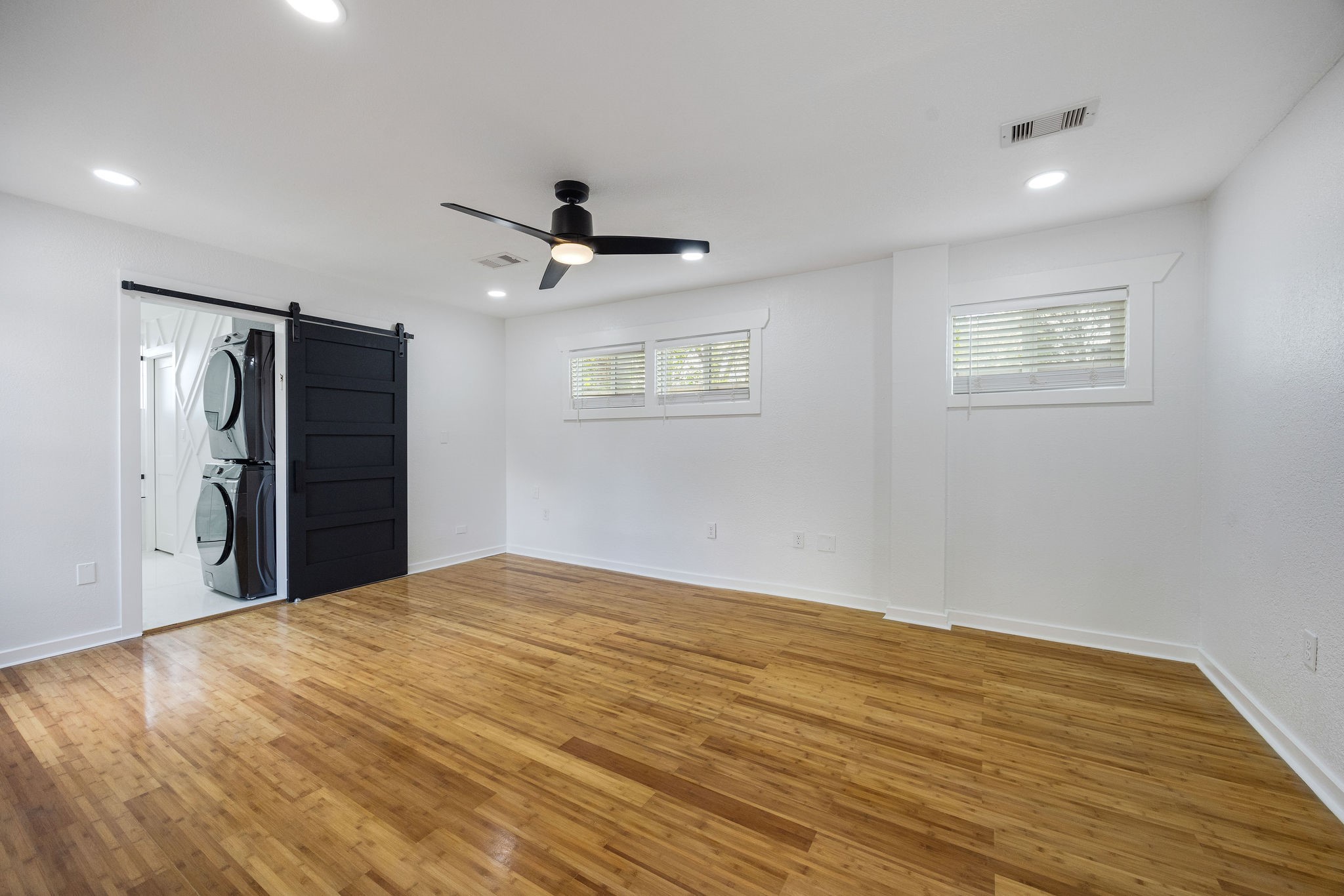 1310 Walton Street Houston, TX 77009 - Photo 10 of 19 Spacious primary bedroom with hardwood floors, modern ceiling fan, and direct access to ensuite bath and laundry.