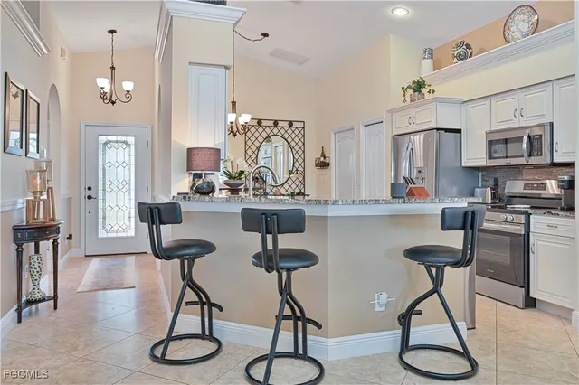 a kitchen with stainless steel appliances granite countertop a refrigerator a stove a dining table and chairs with wooden floor